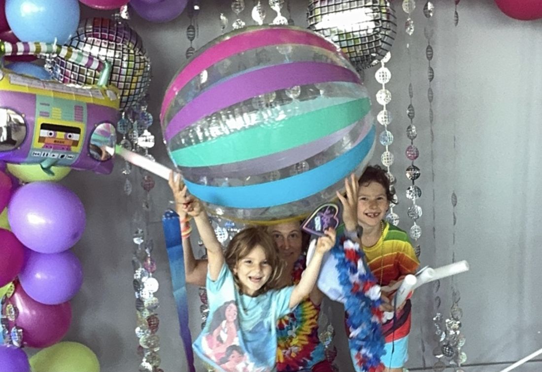 Two kids lifting a giant beach ball with their mom