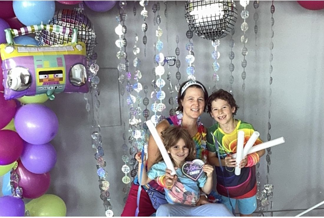 A mom and two kids waving glow sticks at the photo booth