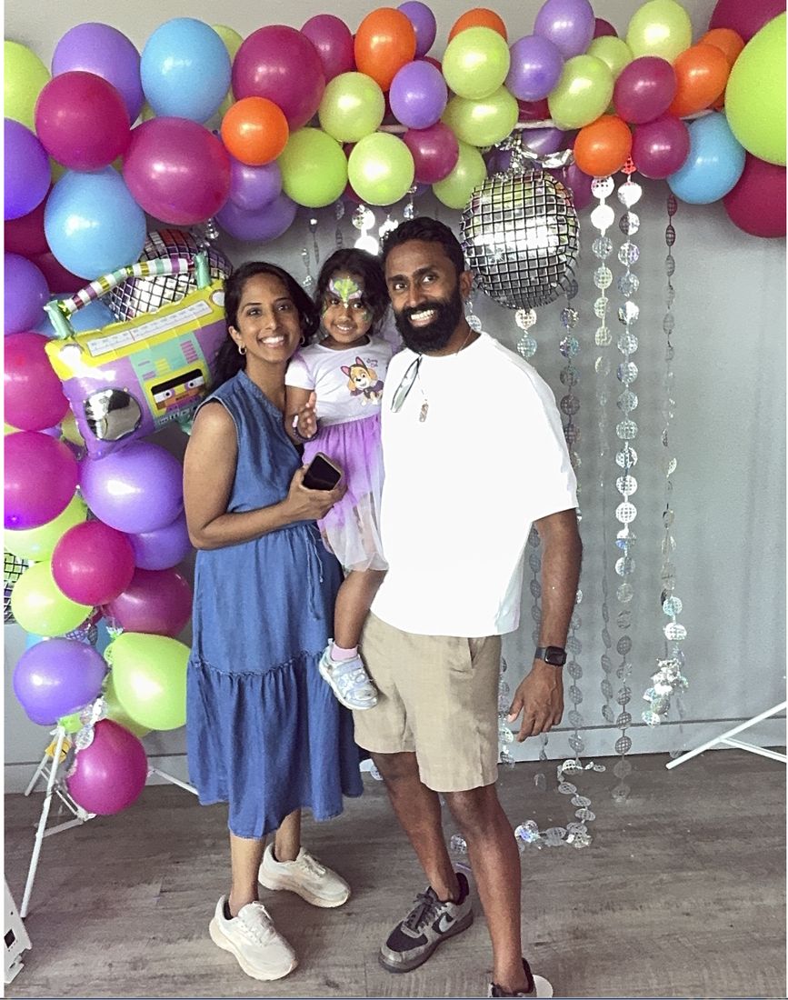 A mom, dad and toddler smiling together at the Tiny Rave photo booth
