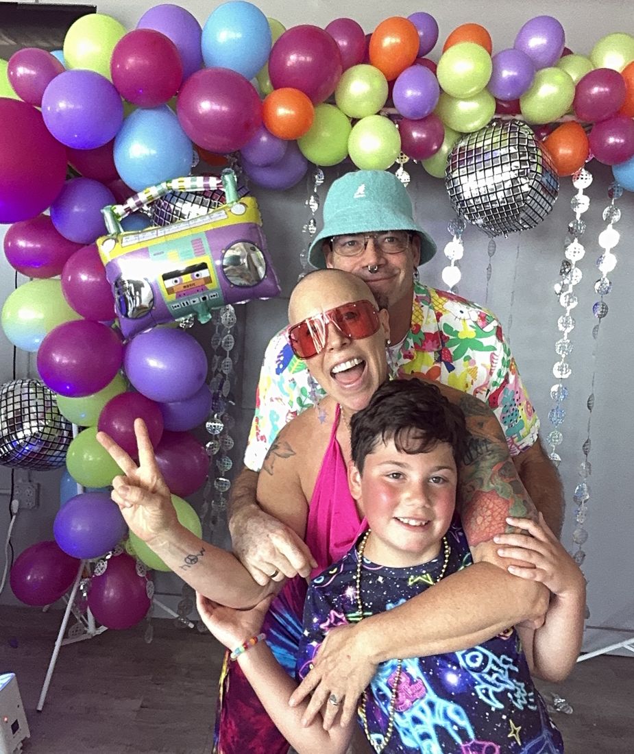 A mom, dad and son grinning and throwing peace signs