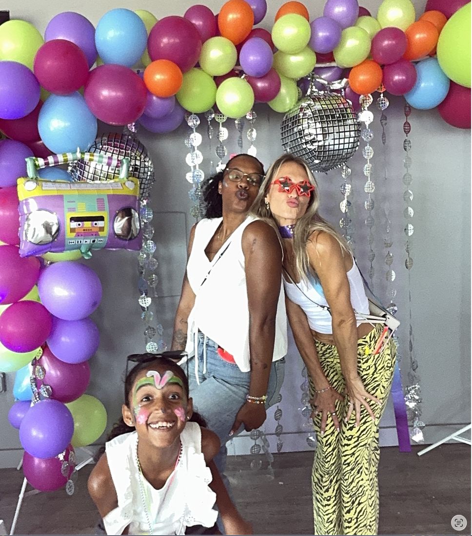 Two moms and a face-painted girl laughing together